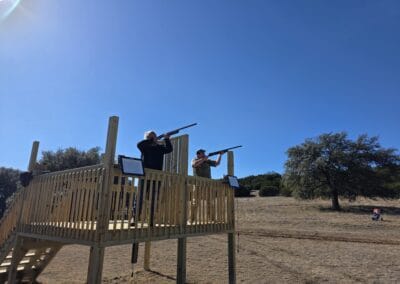 H&H Exotics outdoor shooting range with two people aiming rifles on a wooden platform.